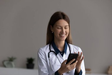 Randevu almak için akıllı telefondaki uygulamayı kullanan mutlu kadın doktor.