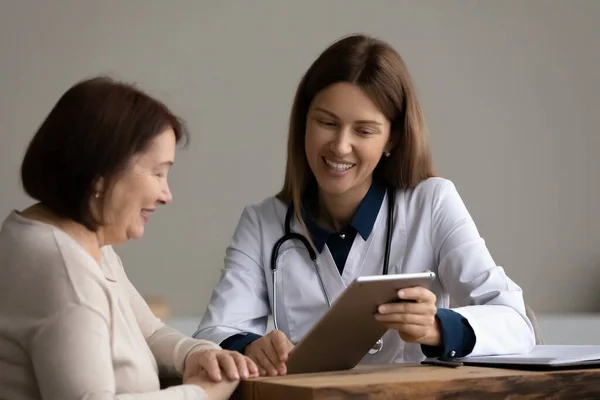 Счастливый оптимистичный врач показывает скриншот старому пациенту на пенсии — стоковое фото