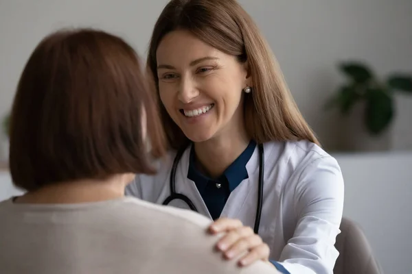 Happy doctor giving support to elder patient, touching shoulder — 图库照片