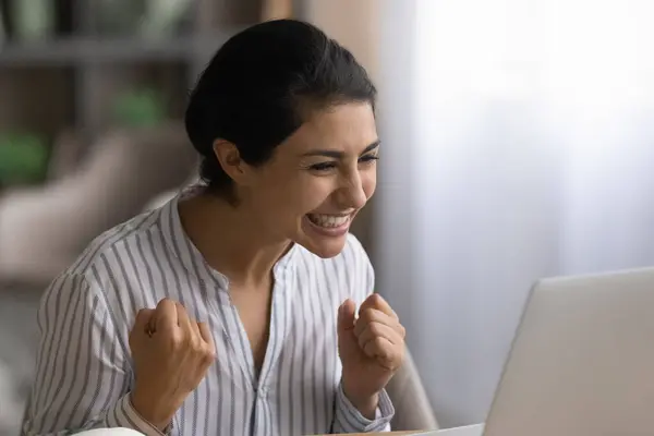 Mujer india alegre triunfa leyendo buenas noticias en el ordenador portátil — Foto de Stock