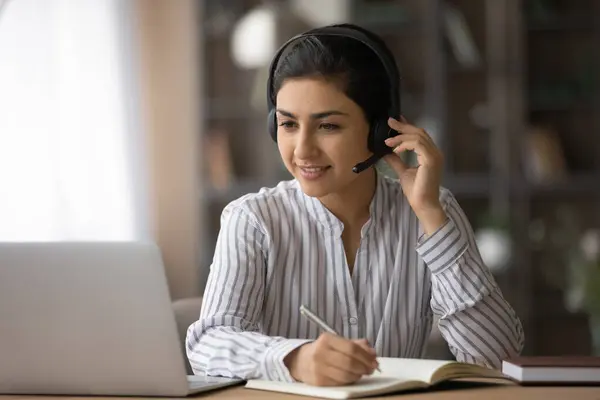 Indian kobieta w słuchawki pracy online na laptopie — Zdjęcie stockowe