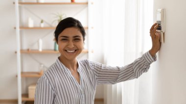 Akıllı ev sistemini kullanan gülümseyen Hintli kadının portresi.