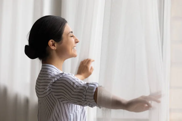 Happy dreamy beautiful Indian woman opening curtains, starting new day — Stok Foto