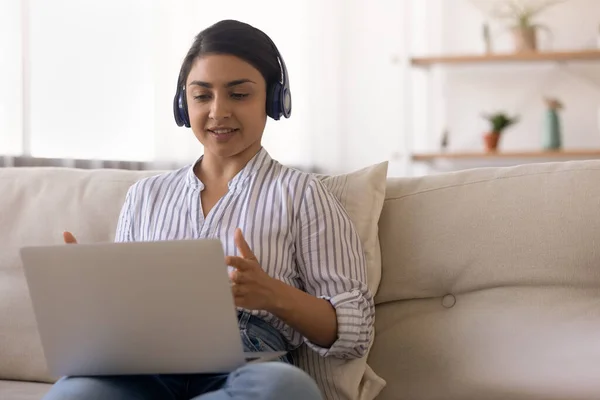 Indian woman in headphones chatting online at home, using laptop — Stock Photo, Image