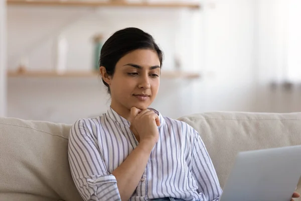 Close up focused Indian woman using laptop, sitting on couch — Stock Photo, Image