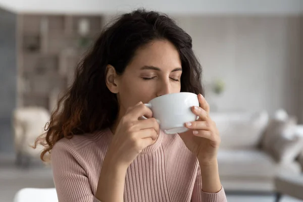 Happy Latin woman enjoy coffee in mug