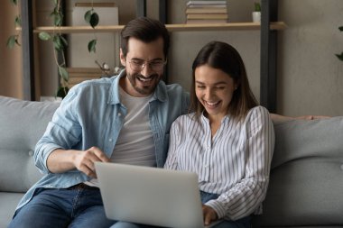 Gülen çift kanepede otururken komik internet içeriğinin tadını çıkarıyor.