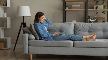 Kanepede oturan kadın internetten bilgisayar alıyor.