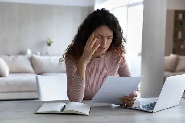 Upset Latino woman distressed with bad news in paperwork — Stock fotografie