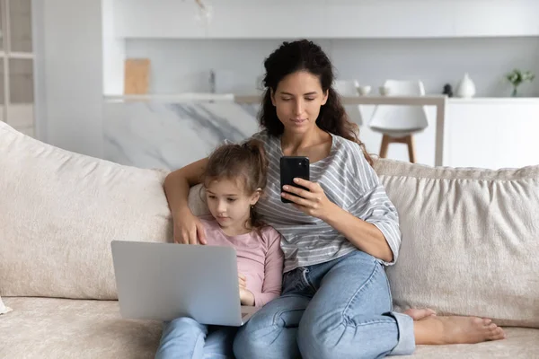 Hispanic mom and teen daughter use gadgets — Foto de Stock