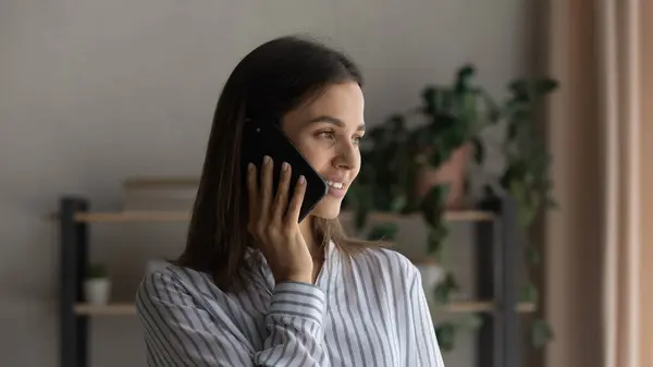 Счастливая красивая женщина разговаривает по телефону, отводя взгляд — стоковое фото