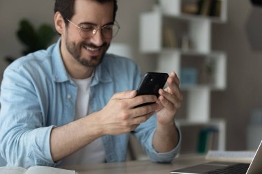 Mutlu iş adamı akıllı telefon kullanarak dikkati dağılmış bir şekilde masada oturuyor.