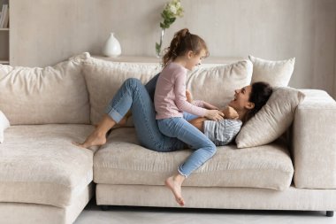 Aşırı neşeli Latin anne ve genç kız evde oynuyorlar.