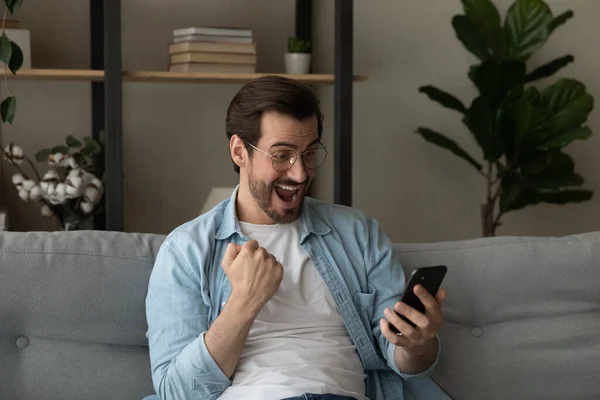 Adam sevinçle cep telefonu çığlıklarına bakıyor. Harika haberleri kutluyor. — Stok fotoğraf