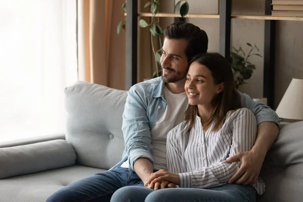 Loving couple relax on sofa cuddling daydreaming looking into distance — Foto Stock
