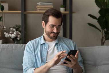 Bekar adam kanepeye oturur, akıllı telefon kullanır, e-flört hizmetleri kullanır.