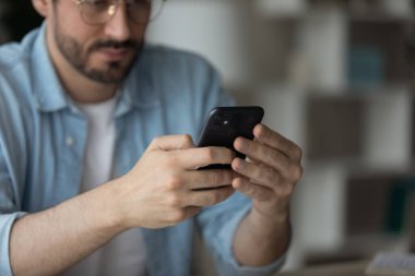 Ciddi bir adam elinde cep telefonu ile masada oturuyor. İşi uzaktan çözüyor.