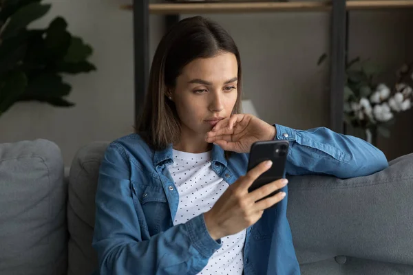 Mujer seria sentarse en el sofá leer sms se siente molesto — Foto de Stock