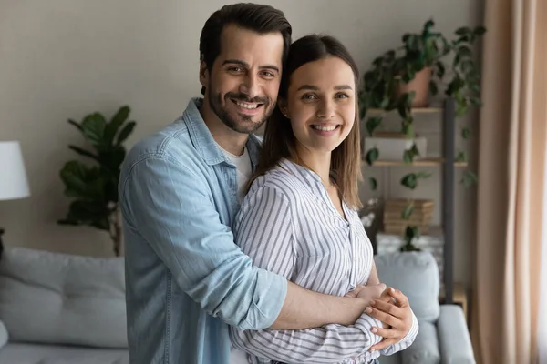 Marido cariñoso abrazar amada esposa sonriendo mirar a la cámara — Foto de Stock