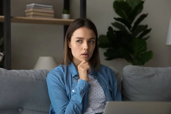 Woman deep in thoughts thinks over task working on laptop — Stock fotografie