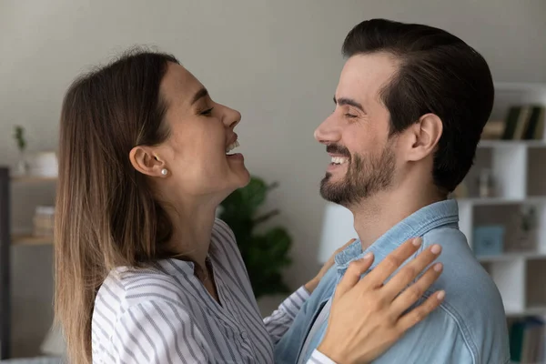 Overjoyed couple looking at each other laughing hugging at home — Stock Photo, Image