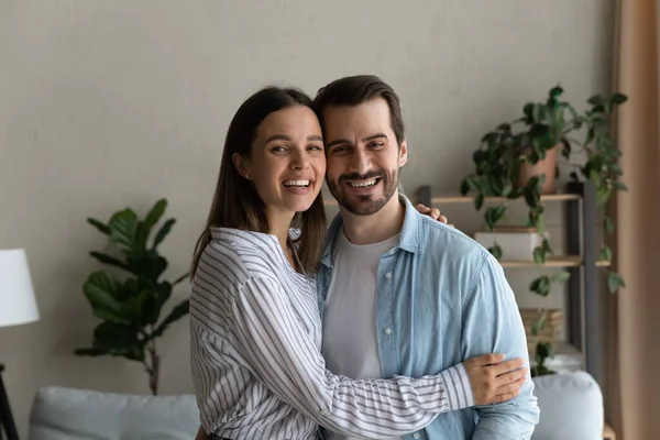 Cheerful laughing married couple hugging posing inside modern house — Foto Stock