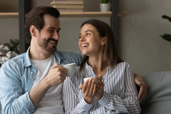 Lovely couple sit on sofa with tea cups enjoy conversation — Foto Stock