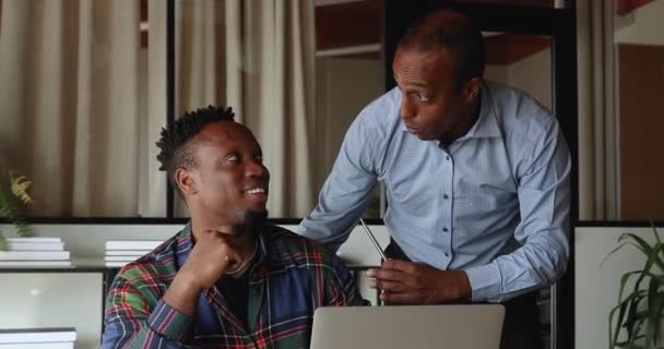 İki neşeli Afrikalı işadamı gülerek ofiste keyifli sohbetler ediyor. — Stok video