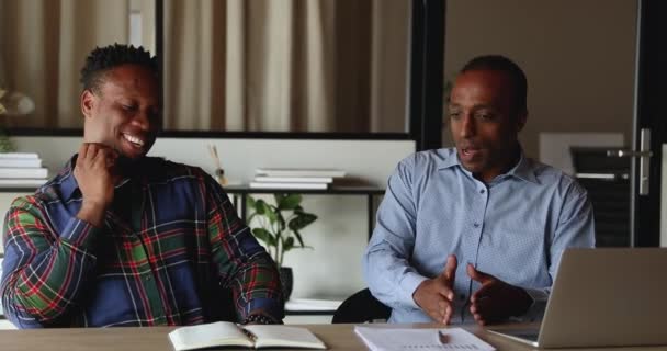 Des collègues africains plus jeunes et plus âgés parlent assis au bureau du lieu de travail — Video