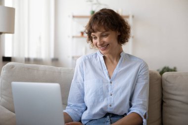 Gülümseyen, rahat, 40 'lı yaşlarda dizüstü bilgisayar kullanan bir kadın..