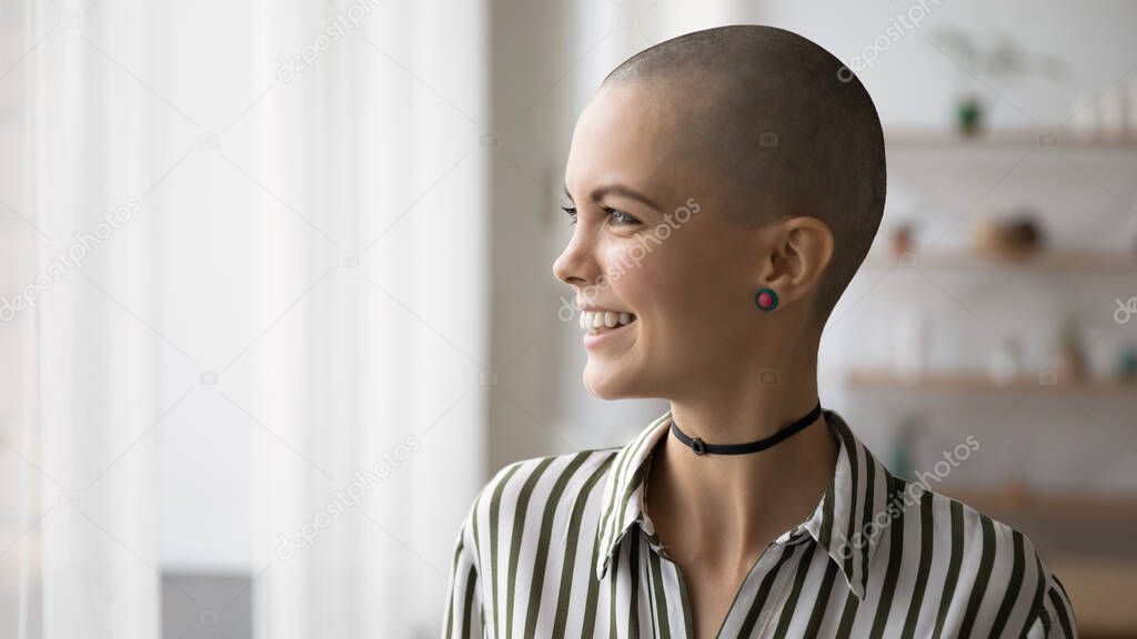 Happy young bald stylish woman looking in distance.