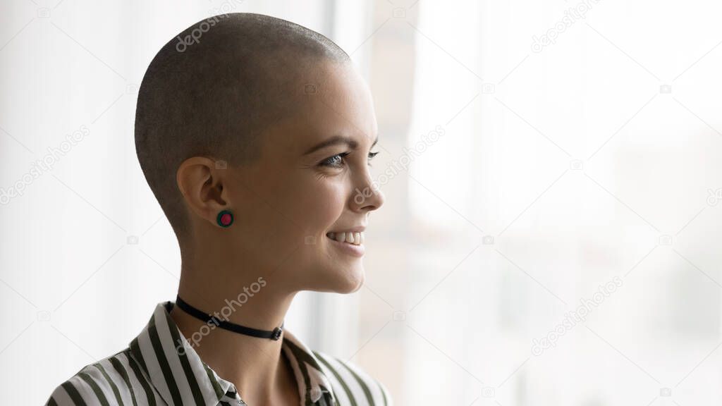 Pretty woman with shaved bald head looking in distance.
