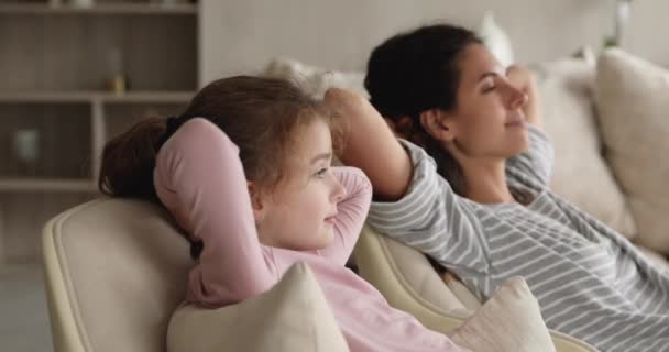 Bezstarostná mladá matka a malá dcera odpočívající na pohovce. — Stock video