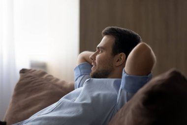 Sakin, mutlu, genç iş adamı rahat bir şekilde kanepede dinleniyor.