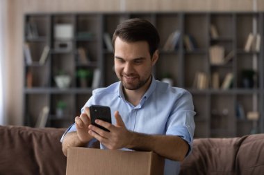 Mutlu milenyum erkek müşterisi paketleri boşaltmak için cep telefonu kullanıyor.