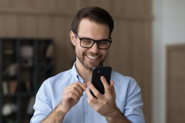 Gülümseyen genç adam cep telefonunu tut ve iyi bir mesaj oku.