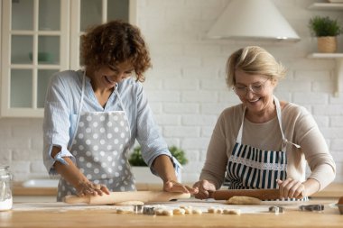 Olgun annesi olan mutlu bir kadın yemek pişiriyor, hamuru yuvarlıyor.