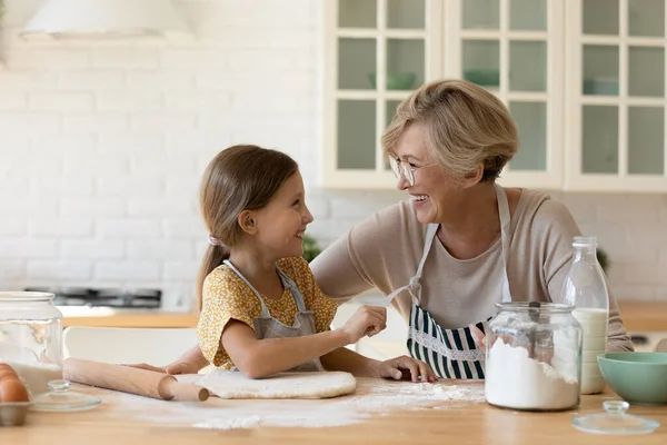 Gelukkig grootmoeder en schattig klein meisje koken in keuken samen — Stockfoto