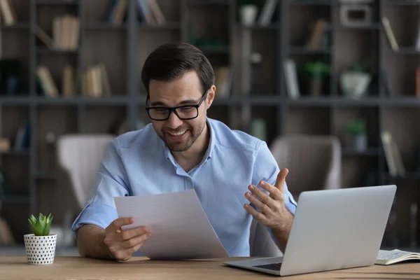 Laughing young man editor reading printed draft of funny article — Stock Photo, Image