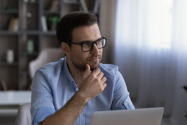 Pensive młody człowiek praca na laptopie online patrzeć na bok myśleć — Zdjęcie stockowe