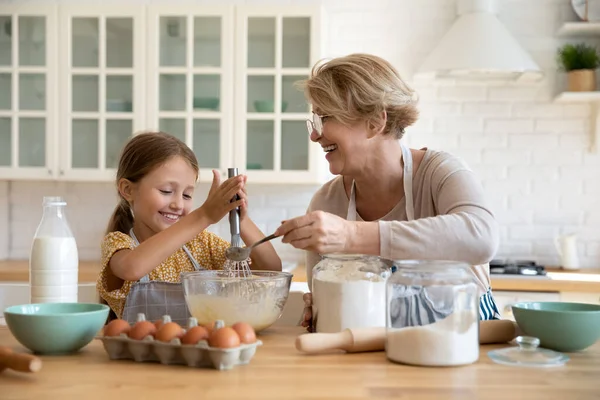 Sorrindo menina com avó madura cozinhar assar juntos — Fotografia de Stock