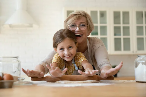 Cabeza retrato feliz abuela con nieta rodando masa juntos — Foto de Stock