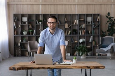 Genç adam, sınıfta dur ve çalışma masasına yaslan.