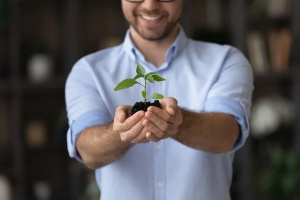 Sorrindo jovem macho mostrar planta a câmera propor proteger a vida — Fotografia de Stock