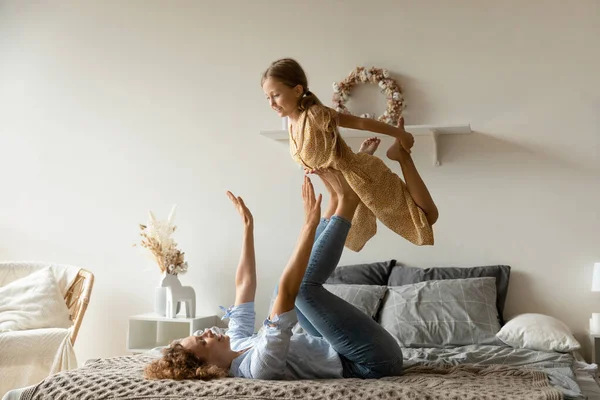 Fuerte madre levantando adorable hijita en las piernas, divertirse — Foto de Stock