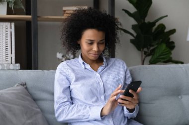 Gülümseyen melez kadın cep telefonunda internet kullanıyor