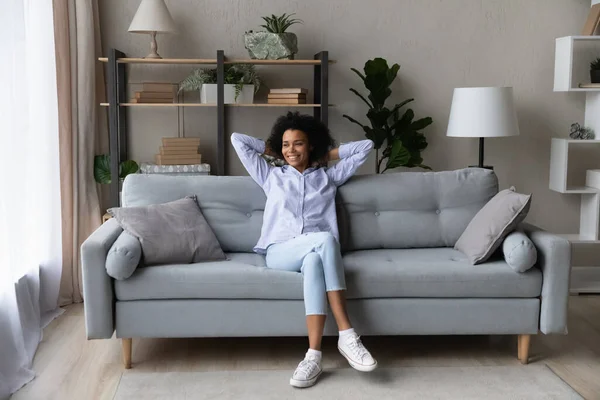 Усміхнена жінка відпочиває на дивані вдома — стокове фото