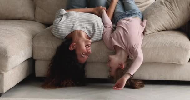 Fröhliche junge Mutter und Kind liegen kopfüber auf Sofa. — Stockvideo
