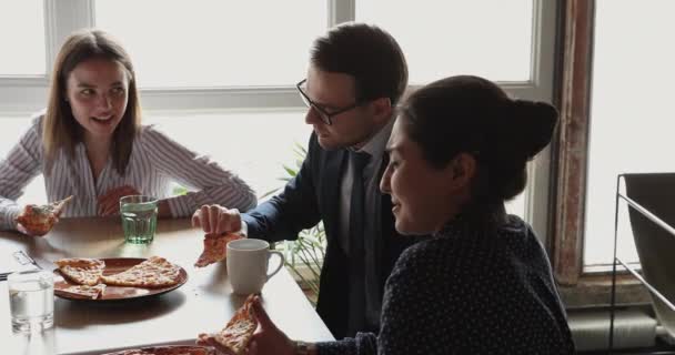 Различные офисные работники разговаривают и наслаждаются пиццей во время обеденного перерыва — стоковое видео