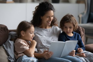 Mutlu anne küçük oğluna ve kızına kitap okuyor.